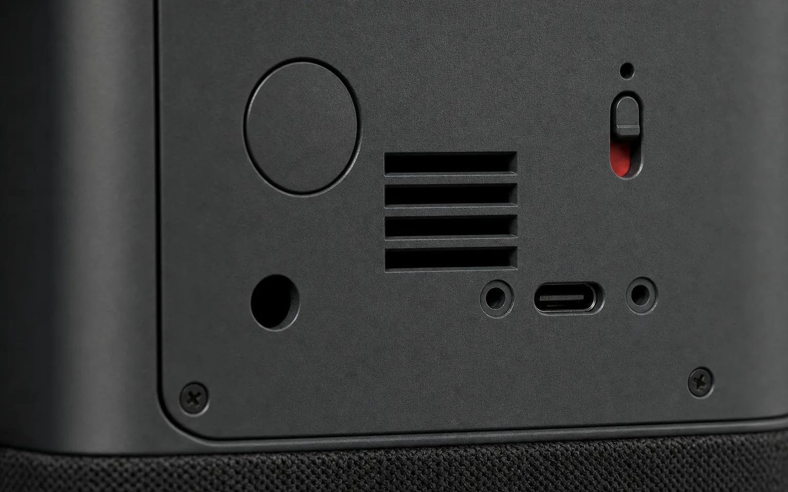 AI-generated concept render of the Nolaka Station's rear panel, built on our CAD — an oblique macro with the microphone mute switch thrown to red and the USB-C socket in focus, the corner and the knit band falling soft.